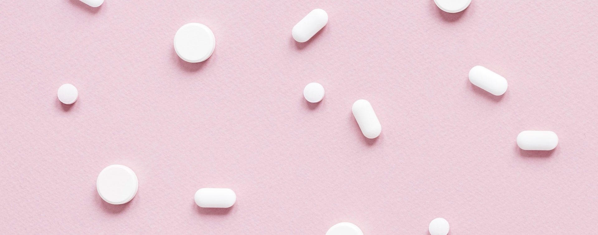 Pilules et Gélules de médicaments blancs posé sur un fond rose pour illustrer la pharmacovigilance