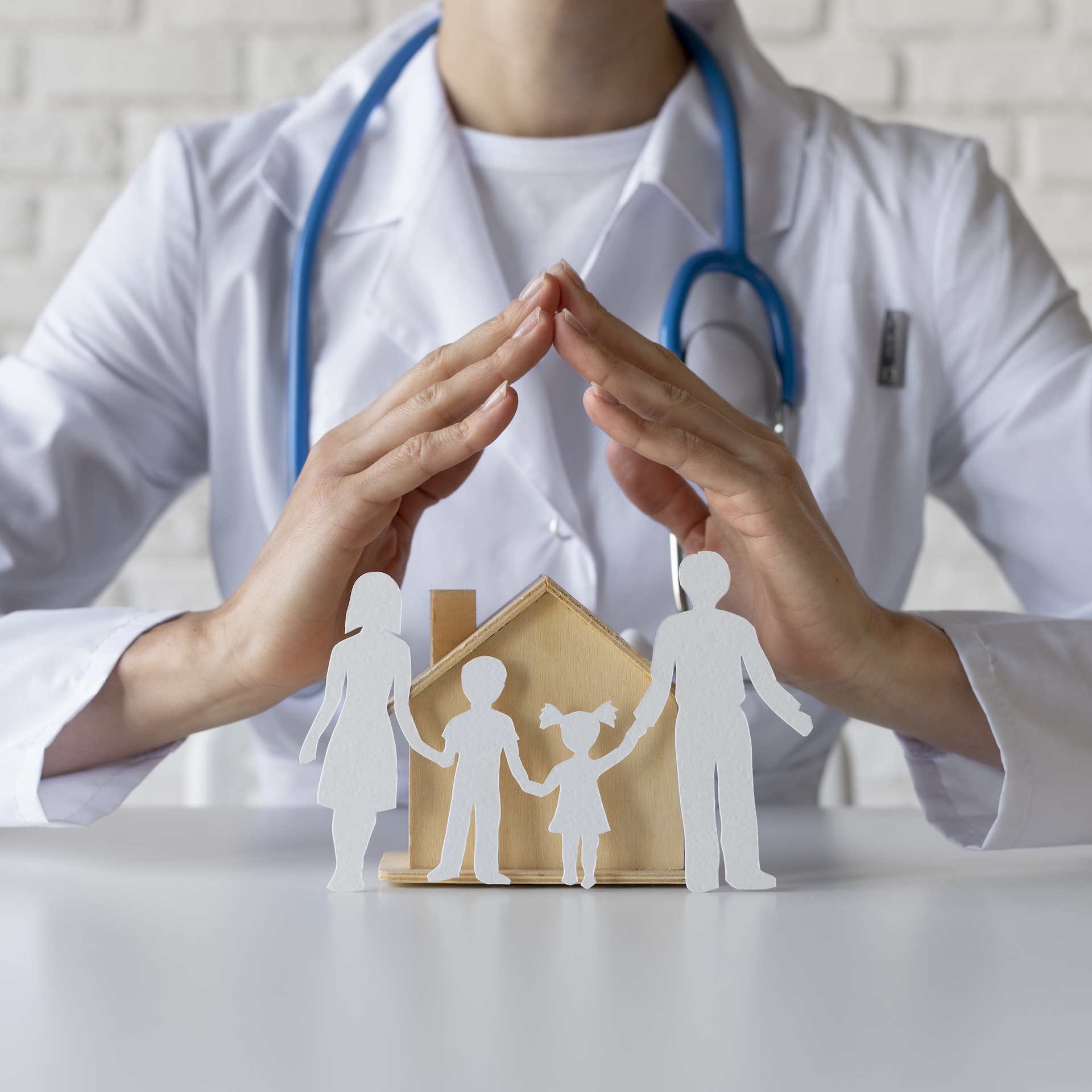 Femme médecin qui entoure symboliquement ses mains au dessus d'une famille pour illustrer le soin, la santé et la prévoyance